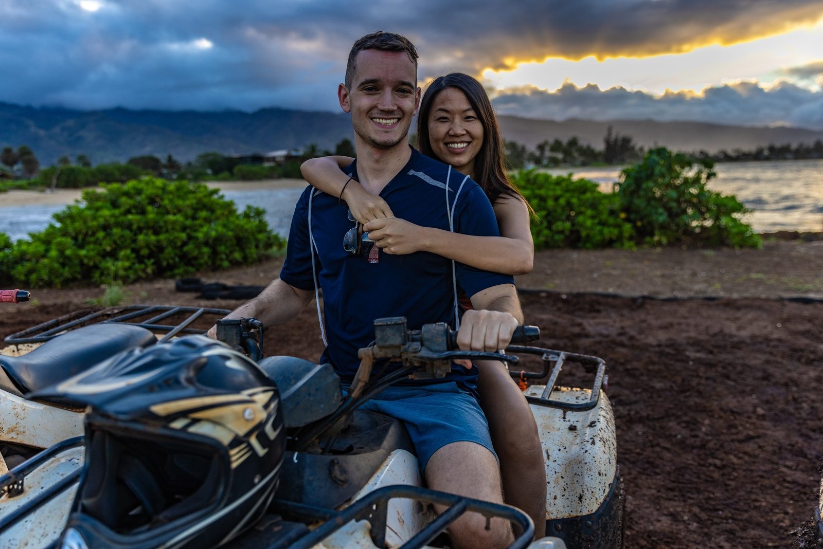 A rider on a green ATV on the sandy track with the Waiʻanae mountains in the distance