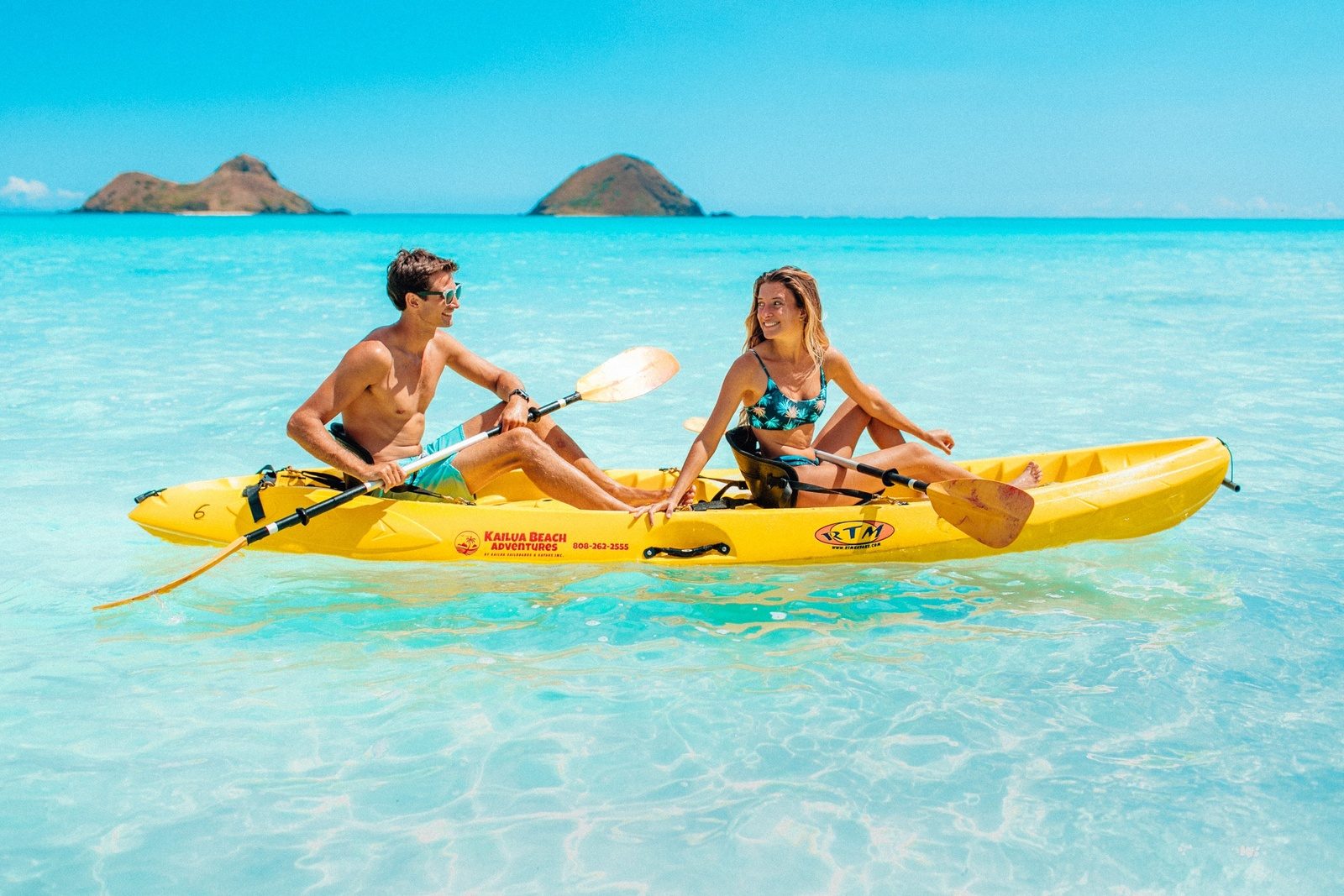 Kayaks pulled up on the small sand beach of Moku Nui with Lanikai and the Koʻolau mountains across the water