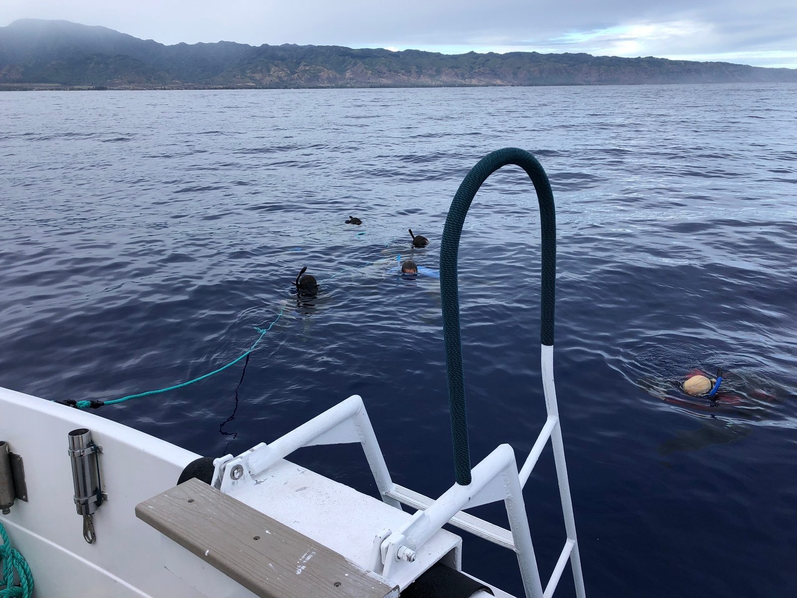 The small tour boat sitting on glassy water three miles off the North Shore with the Waiʻanae mountains behind