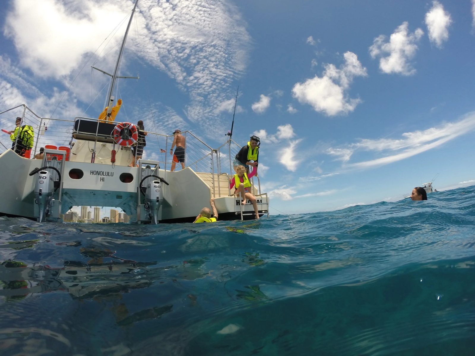 The catamaran pulled up on the sand at Waikiki Beach with guests boarding from the water